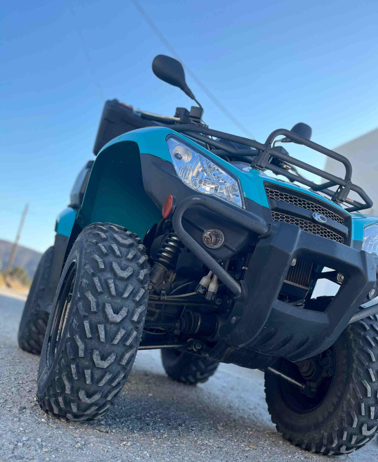 Front view of a light blue ATV on the island of Milos Greece, 4 wheels, headlights shown.