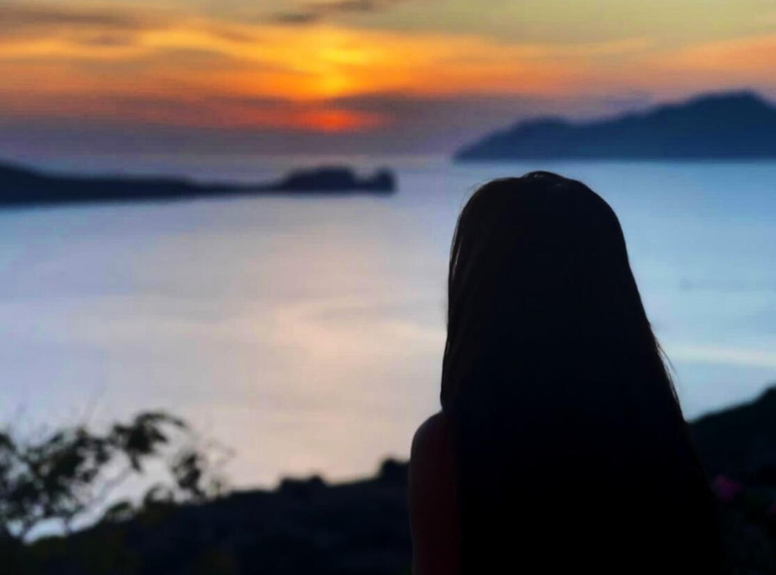 Lady admiring the sunset in Milos, Greece with the golden hour sunset
